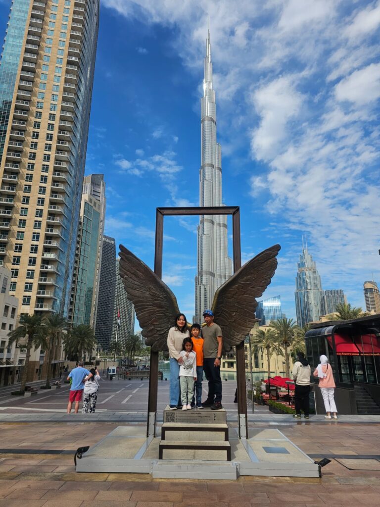 Win, Victory, Love sculpture in Burj Park with Burj Khalifa towering in the background.